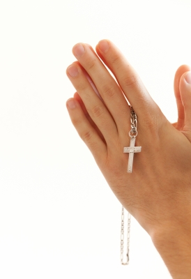 hands in praying position holding a cross on a chain