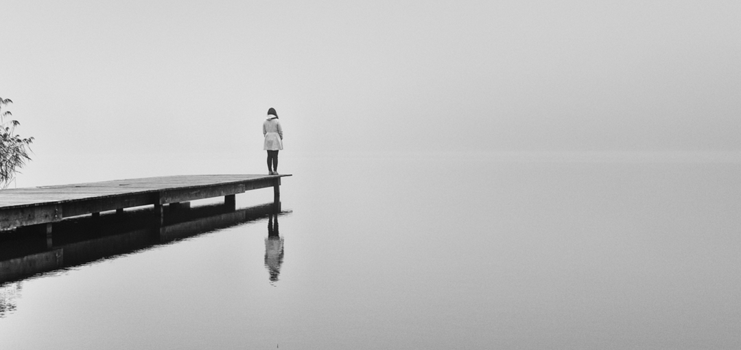 lonely girl standing alone at end of dock dealing with OCD