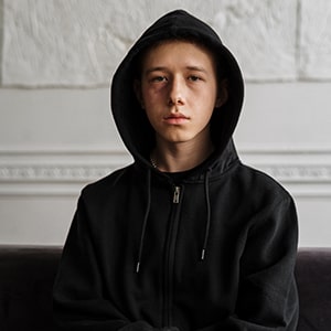 Young teen with sweatshirt hood on after abusing Coricidin.