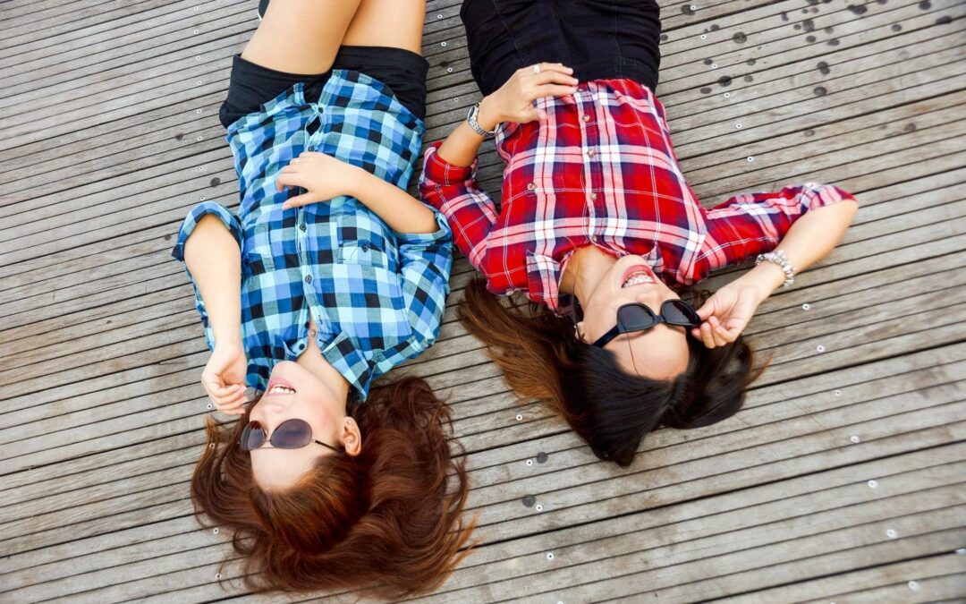 Two friends happily lying on a dock.