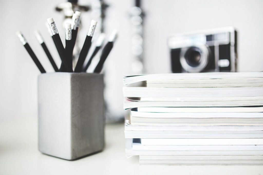 Stack of notebooks on desk and pencils in pencil holder. Improve study habits with good organization.