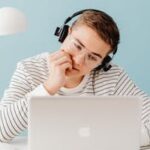 Boy in front of laptop with earphones on doing teletherapy for teens